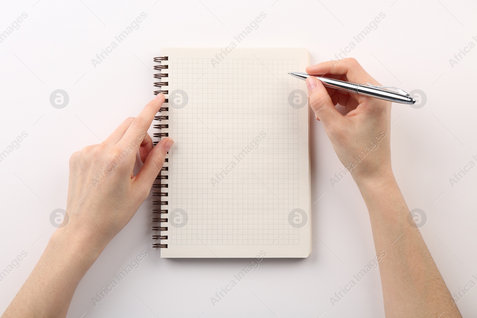 Photo of Woman writing in notebook on white background, top view