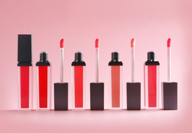 Photo of Liquid lipsticks with applicators on color background