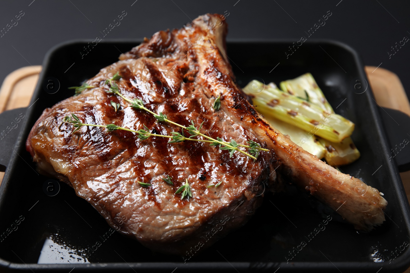 Photo of Grill pan with barbecued meat on wooden board, closeup