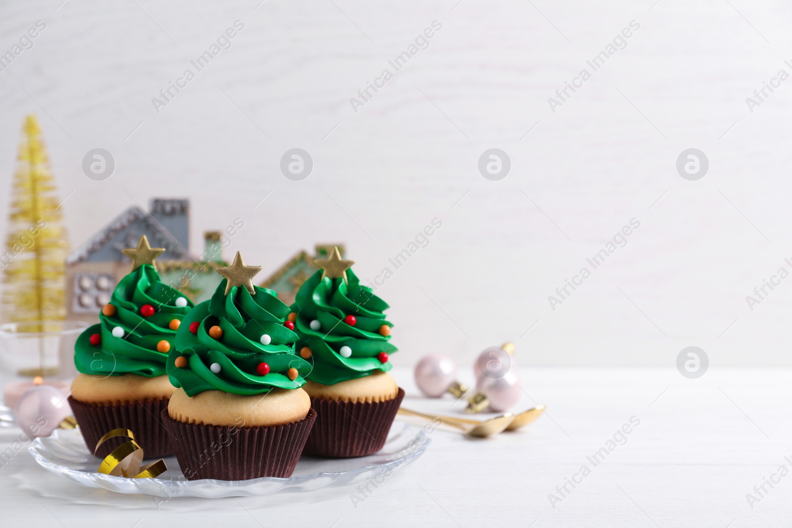 Photo of Christmas tree shaped cupcakes on white table. Space for text