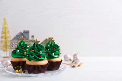 Christmas tree shaped cupcakes on white table. Space for text