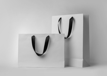 Photo of Paper shopping bags with ribbon handles on white background. Mockup for design