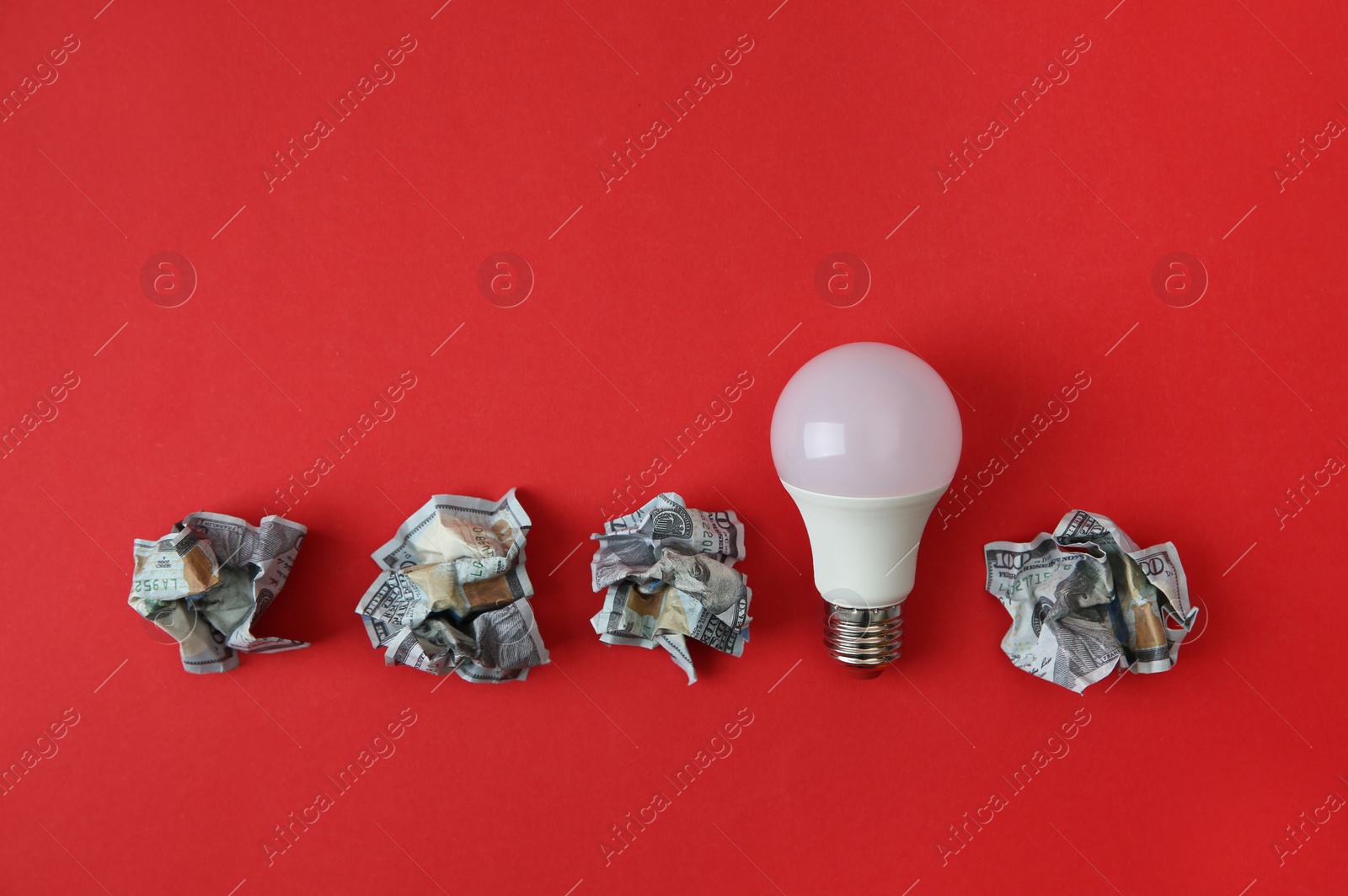 Photo of Flat lay composition with lamp bulb and crumpled money on color background