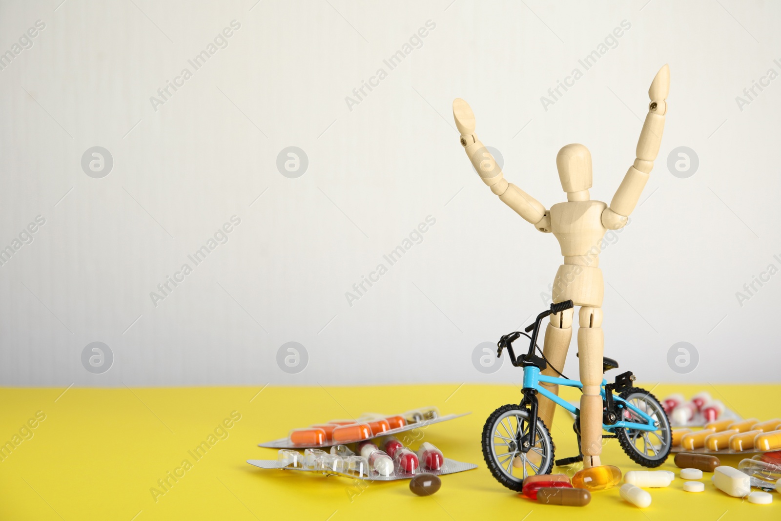 Photo of Pills, sportsman and bike model on yellow table, space for text. Using doping in cycling sport concept