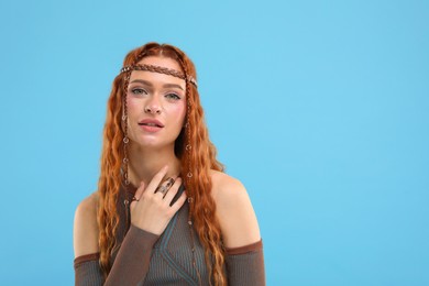 Photo of Beautiful young hippie woman on light blue background, space for text