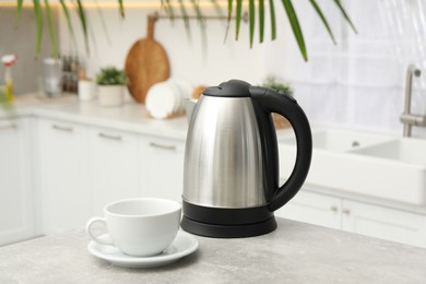 Photo of Electric kettle and cup on table in kitchen