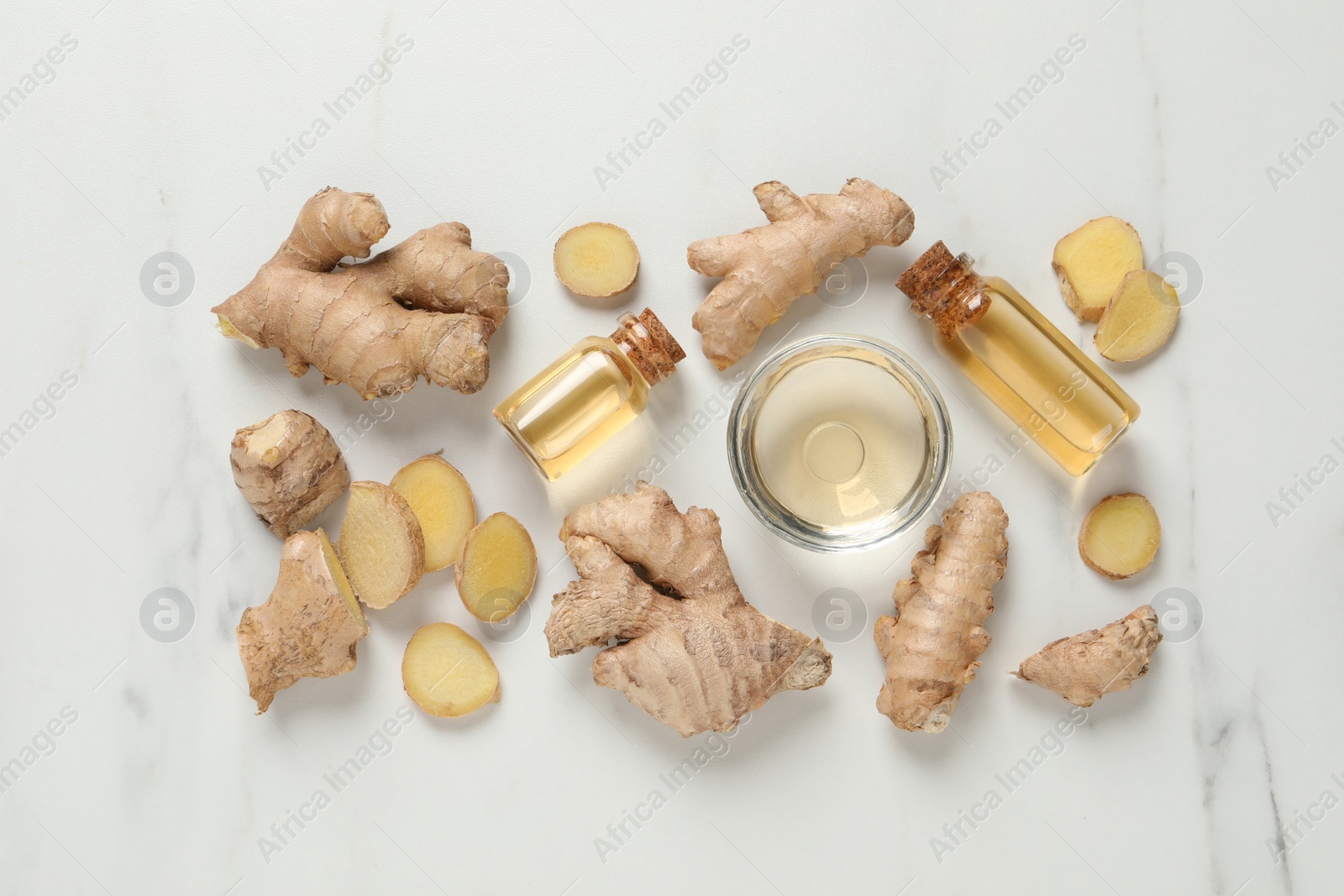 Photo of Glass bottles of essential oil and ginger root on white marble table, flat lay