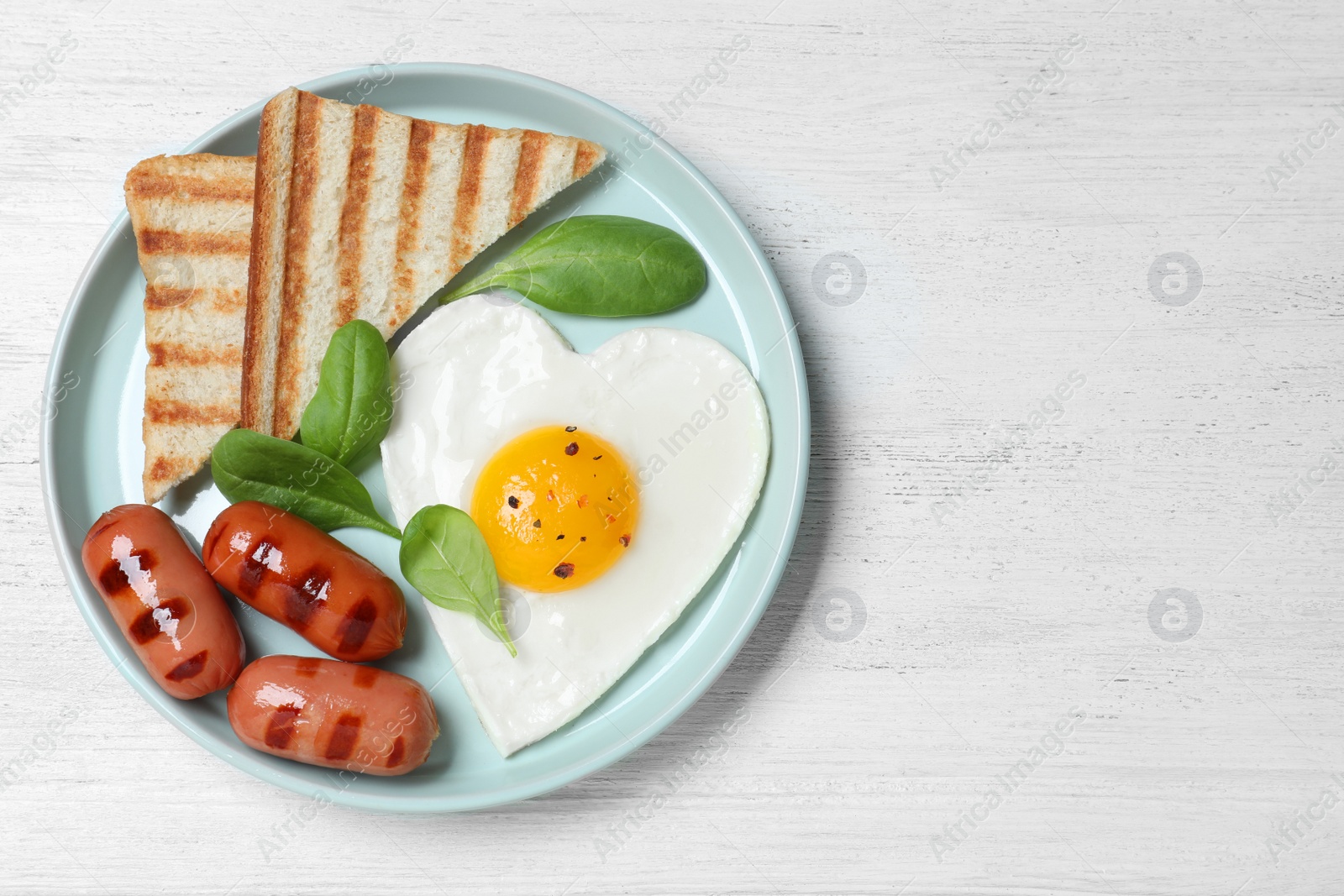 Photo of Plate of tasty breakfast with heart shaped fried egg  on white wooden table, top view. Space for text