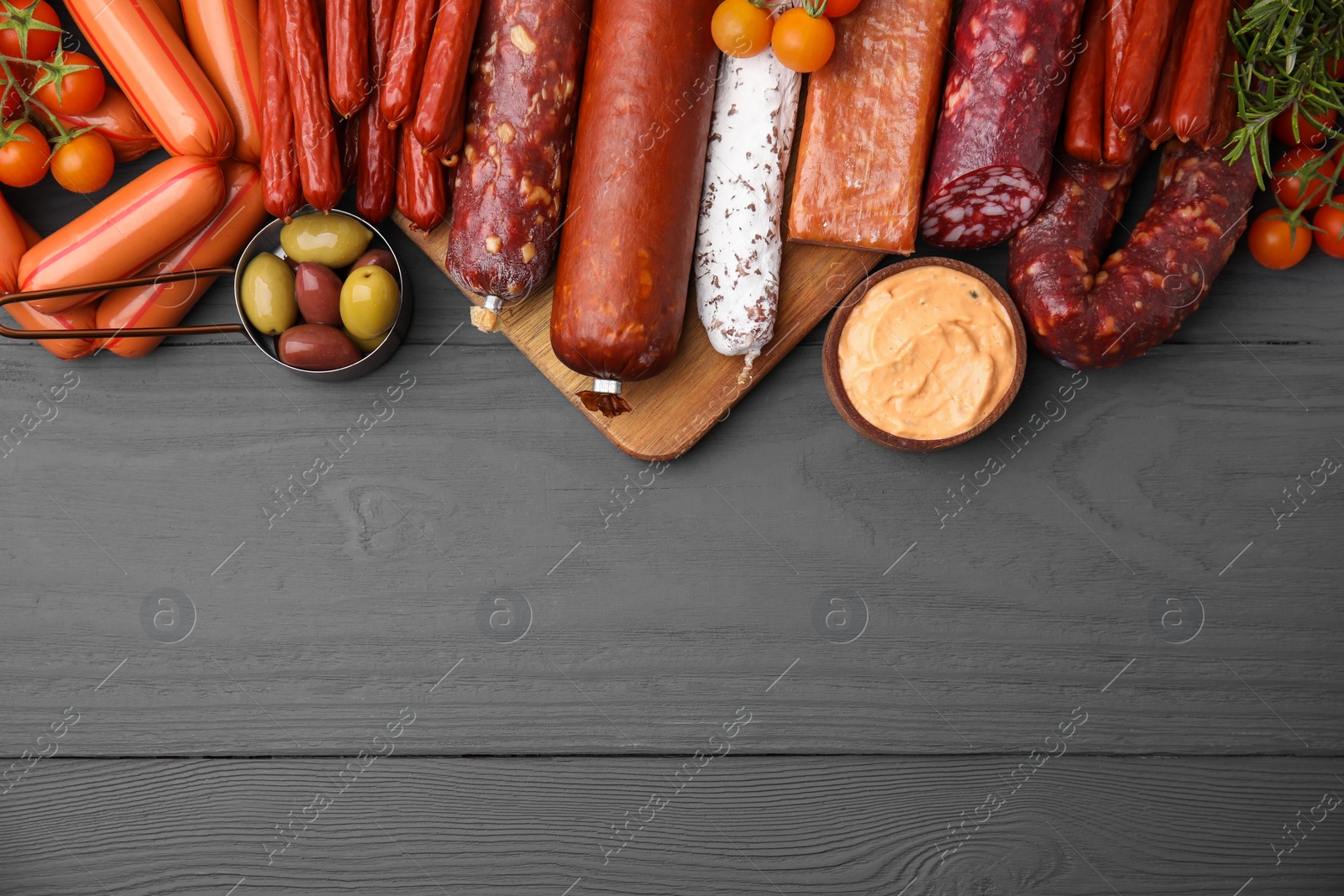 Photo of Different types of tasty sausages on grey wooden table, flat lay. Space for text