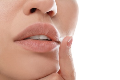 Young woman with cold sore applying cream on lips against white background, closeup