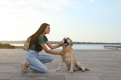 Photo of Young woman with cute golden retriever dog on pier