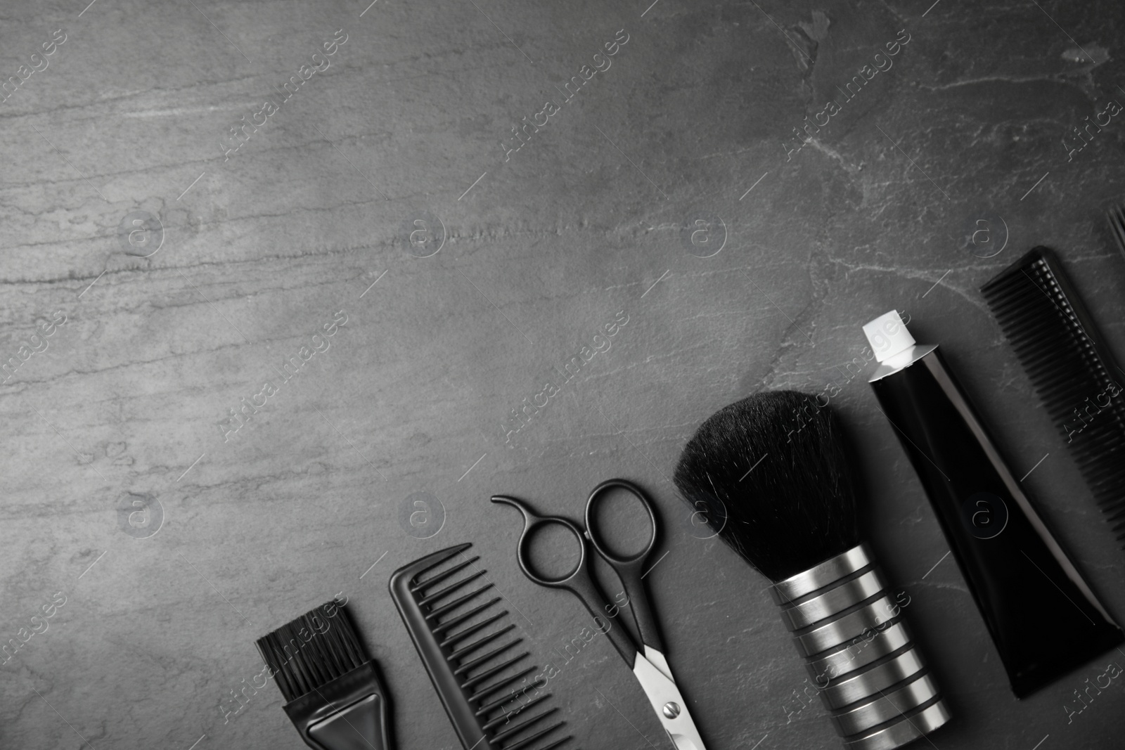 Photo of Professional tools for hair dyeing on black stone background, flat lay. Space for text