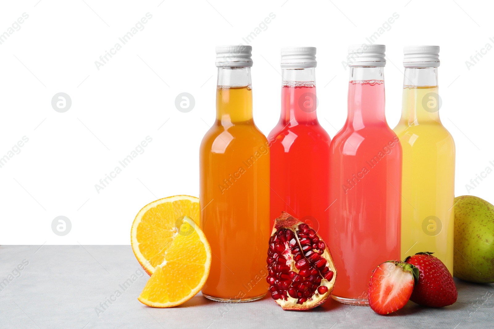 Photo of Delicious kombucha in glass bottles and fresh fruits on grey table against white background