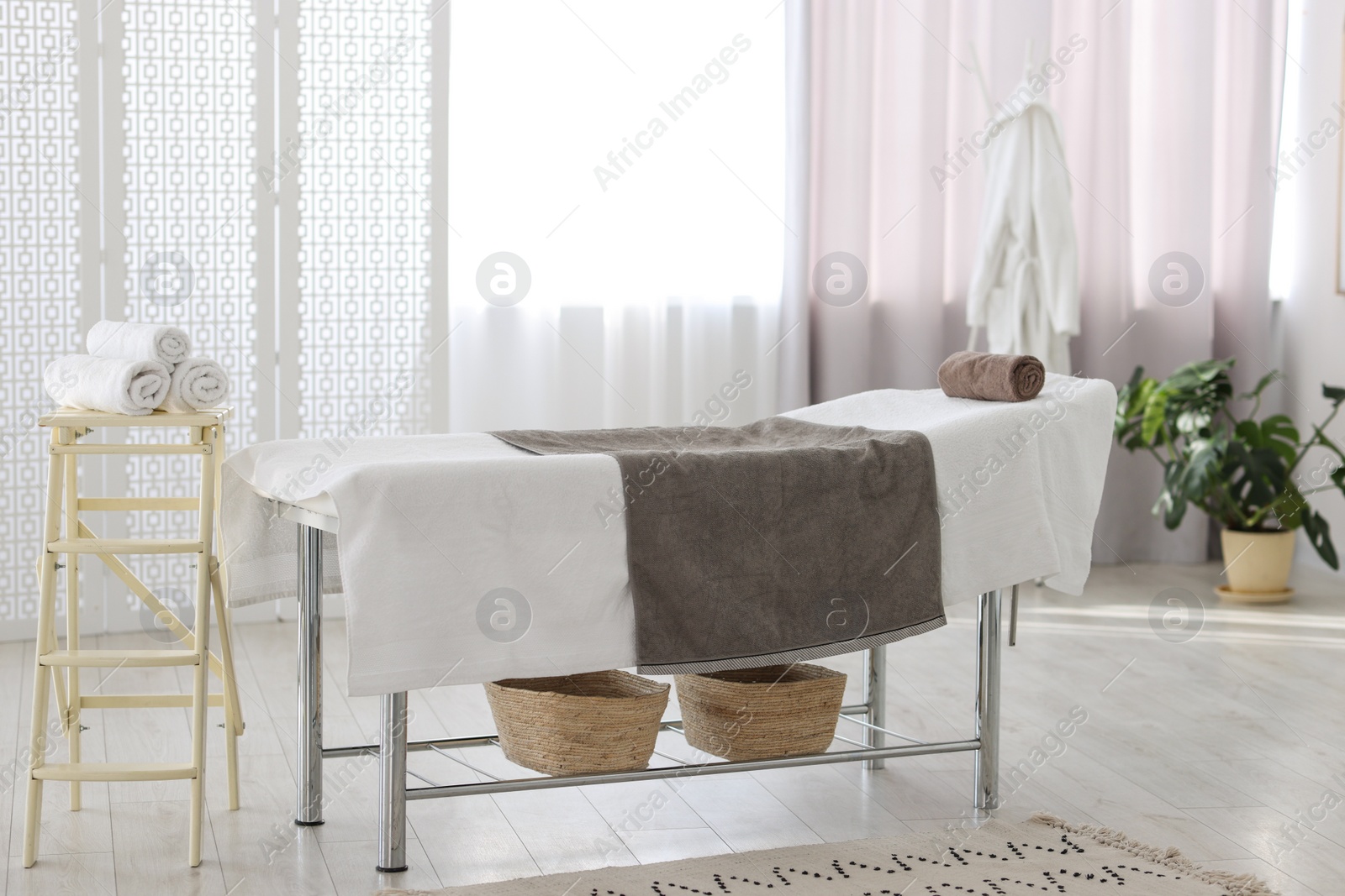 Photo of Comfortable massage table with clean towels in spa center