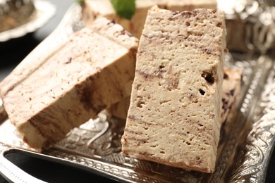 Photo of Pieces of tasty chocolate halva on tray, closeup