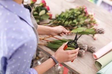 Female florist making beautiful bouquet in flower shop, closeup