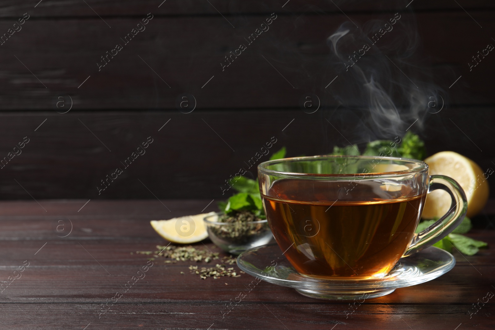 Photo of Glass cup of freshly brewed tea on wooden table. Space for text