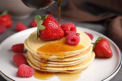 Photo of Tasty pancakes with fresh berries and honey on plate, closeup