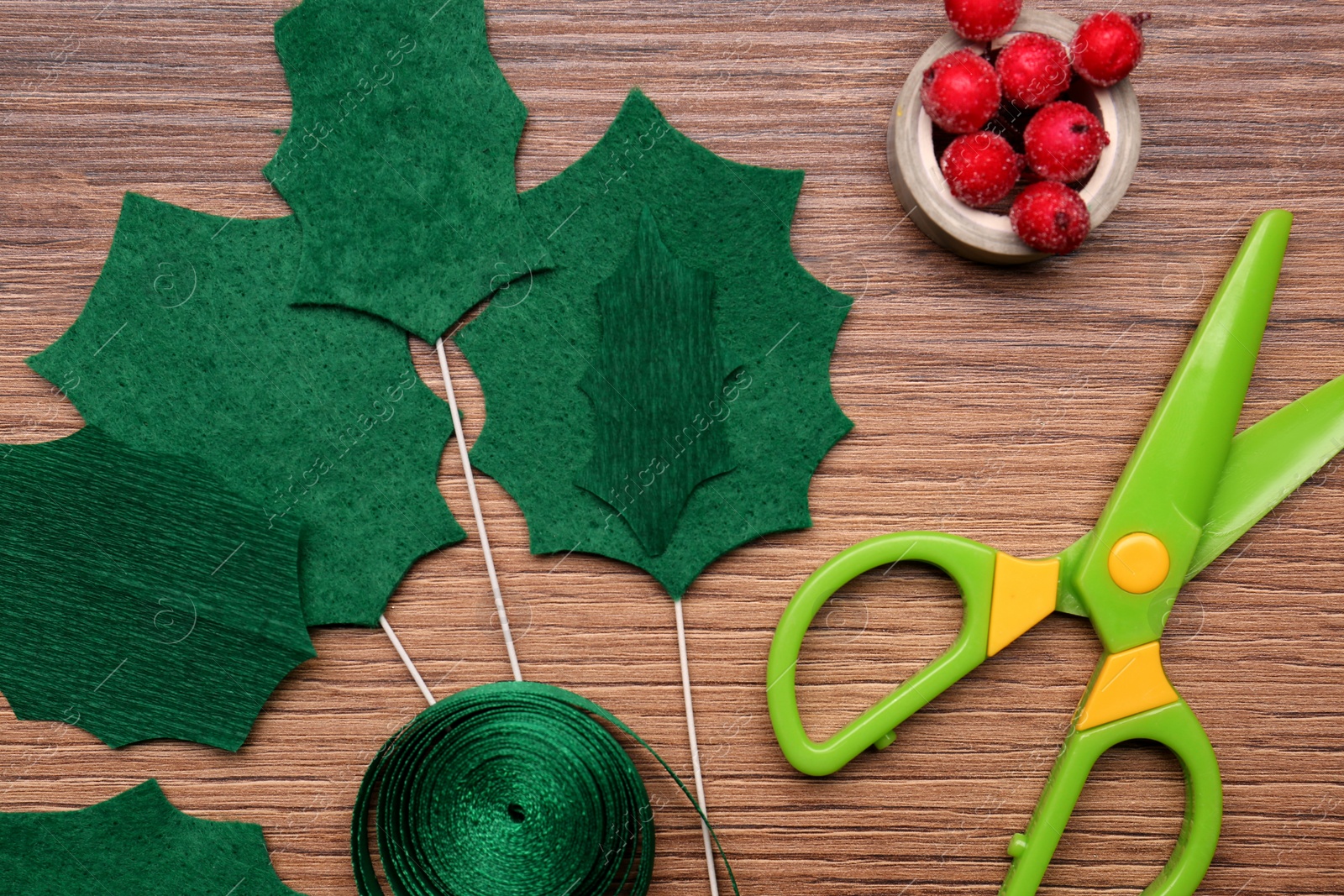 Photo of Set of instruments and materials for making mistletoe branch on wooden table, flat lay