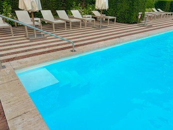 Photo of Outdoor swimming pool in luxury hotel on sunny summer day. Time for relax