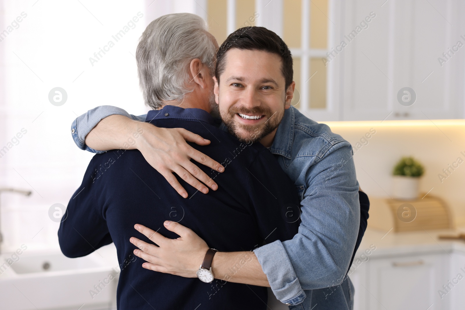 Photo of Happy son and his dad hugging at home