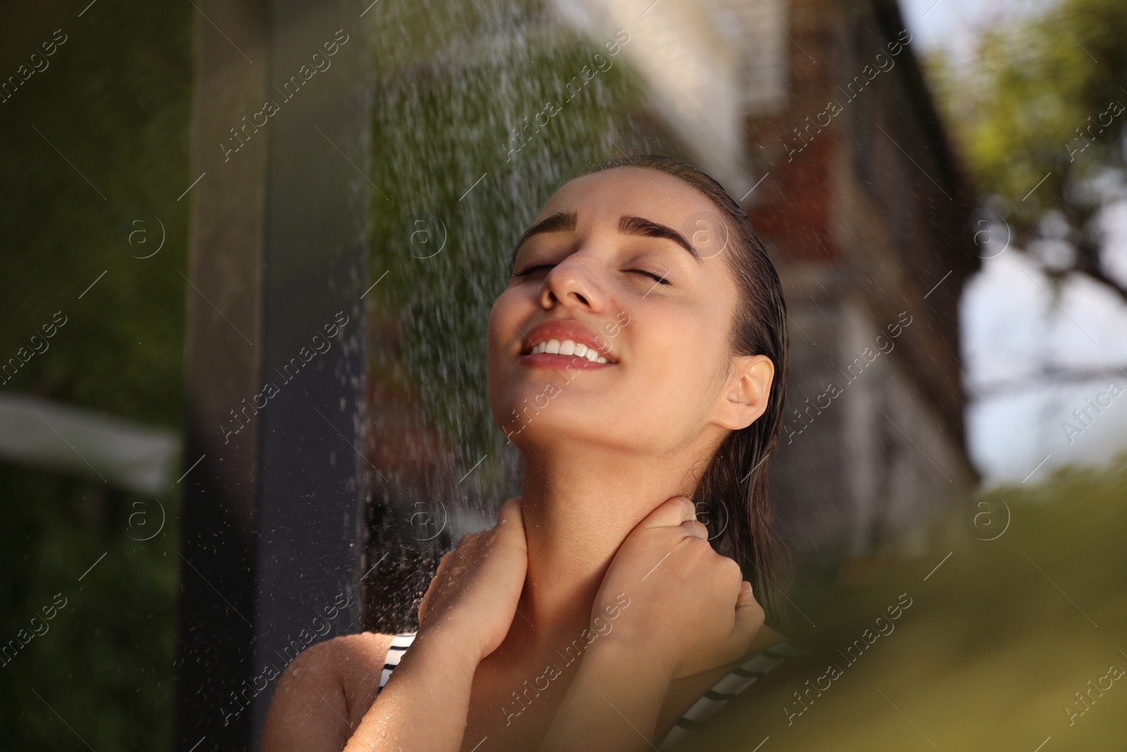 Photo of Woman washing hair in outdoor shower on summer day