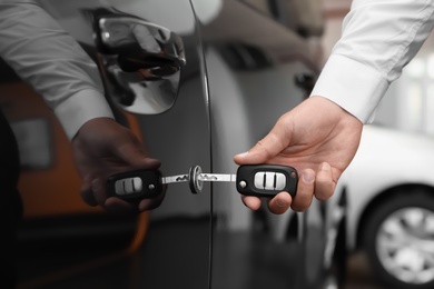 Photo of Young man opening car with key indoors, closeup