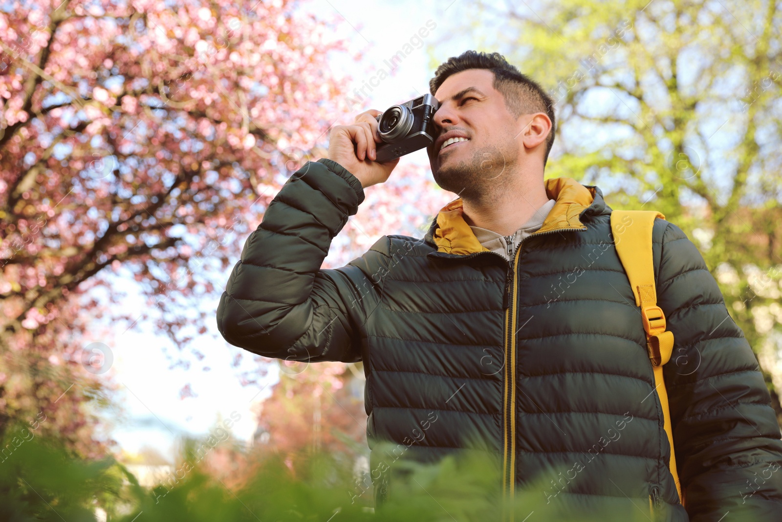 Photo of Happy male tourist with camera outdoors on spring day