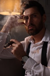 Photo of Handsome man smoking cigar at home in evening