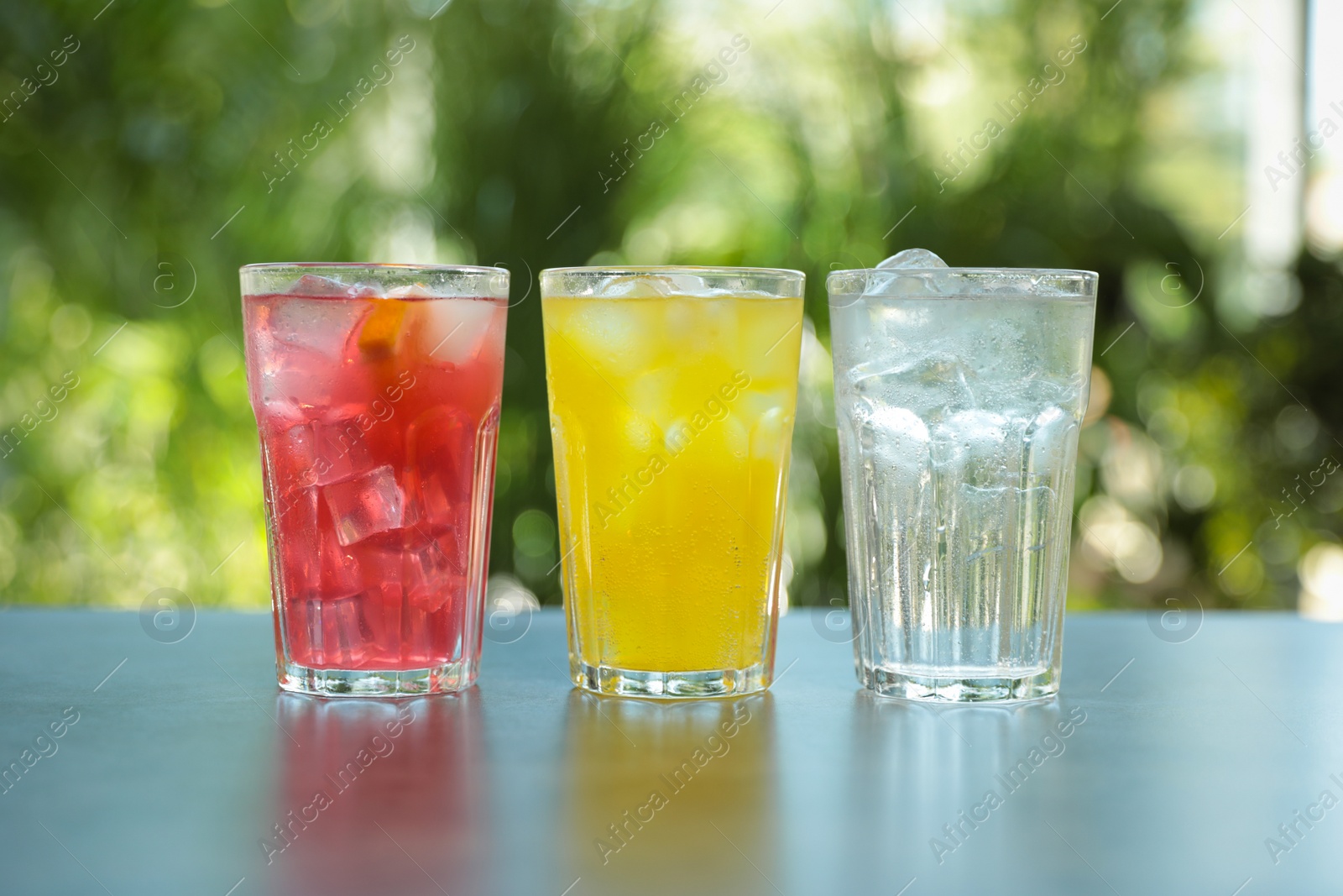 Photo of Delicious refreshing drinks in glasses on grey table outdoors