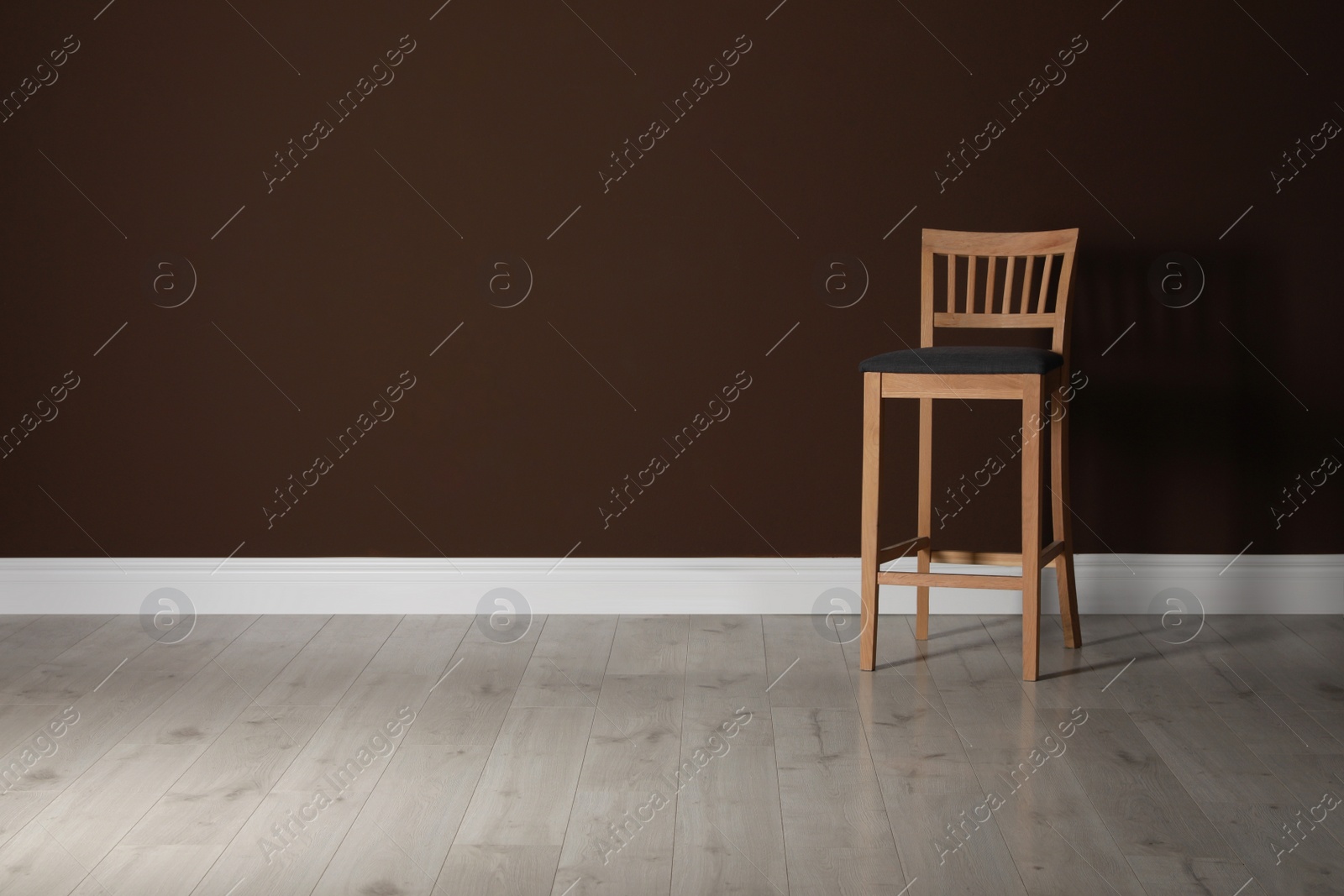 Photo of Stylish bar stool near brown wall indoors. Space for text