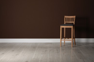 Photo of Stylish bar stool near brown wall indoors. Space for text