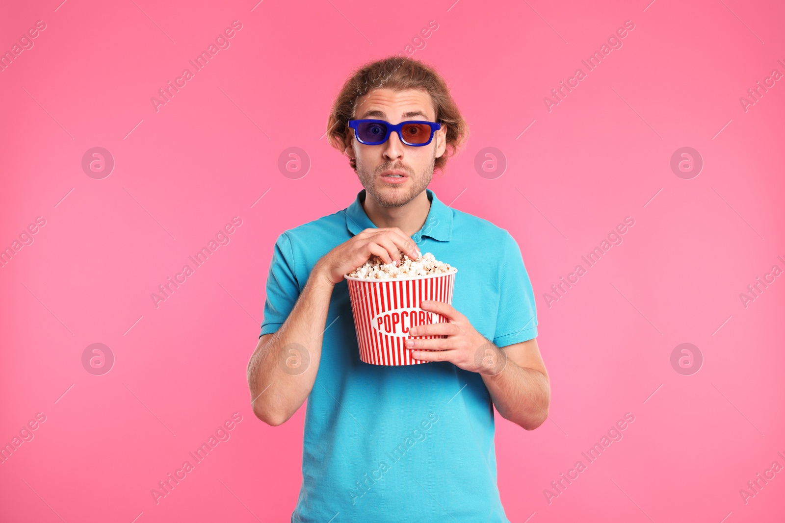 Photo of Emotional man with 3D glasses and popcorn during cinema show on color background