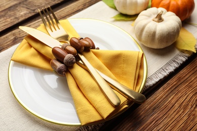 Photo of Autumn table setting with pumpkins and acorns on wooden background, closeup