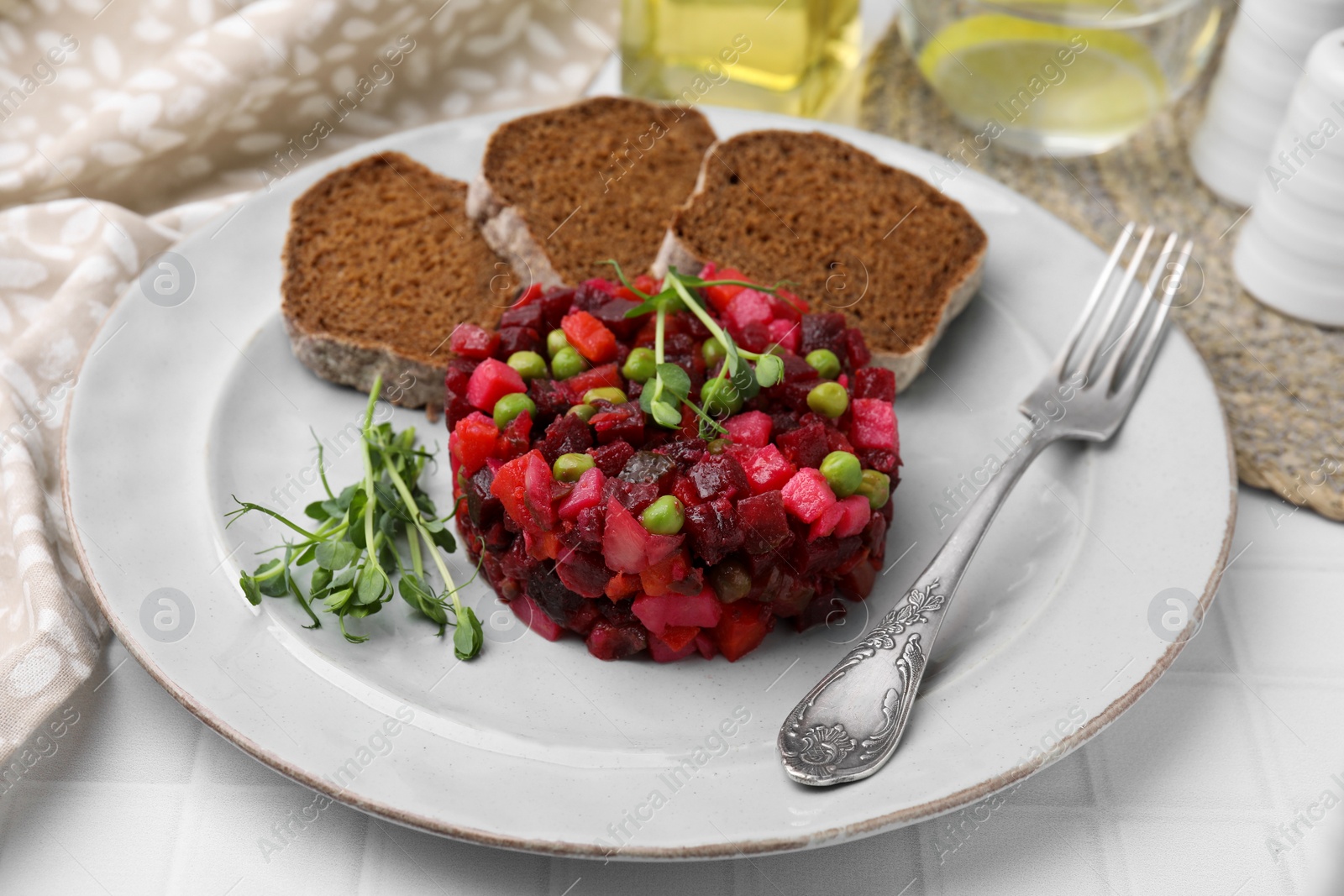 Photo of Delicious vinaigrette salad with slices of bread on white table