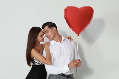 Photo of Beautiful couple with heart shaped balloon on light background