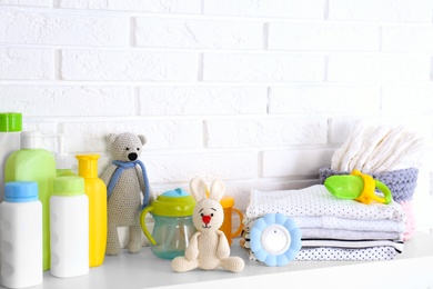 Photo of Baby accessories on shelf near white brick wall. Space for text