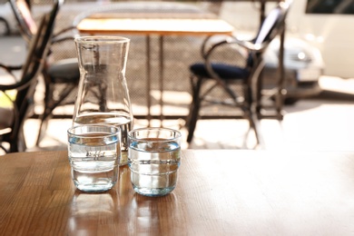 Photo of Glassware with water on wooden table indoors