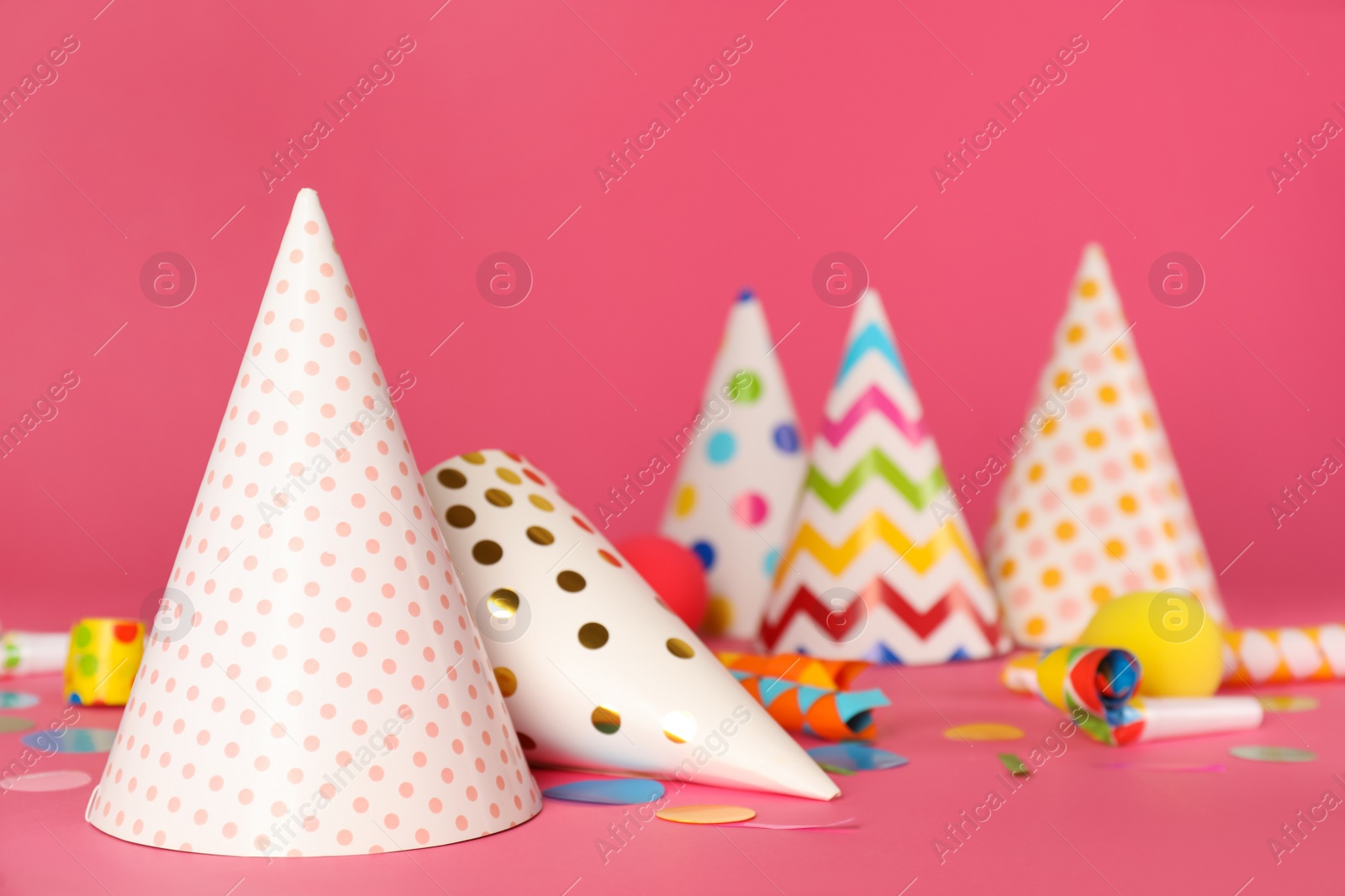 Photo of Party hats and festive items on pink background. Space for text