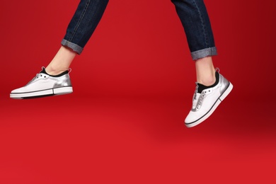 Woman in stylish shoes jumping on color background