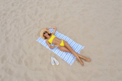 Image of Woman sunbathing on beach towel at sandy coast, aerial view