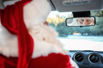 Authentic Santa Claus looking into rear view mirror inside of car