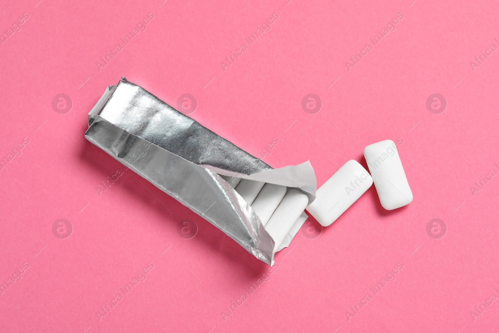 Photo of Pack with tasty chewing gums on pink background, flat lay