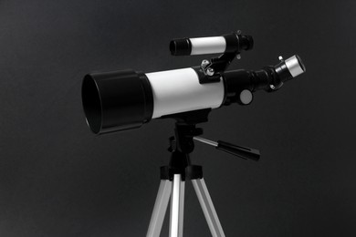 Tripod with modern telescope on black background, closeup