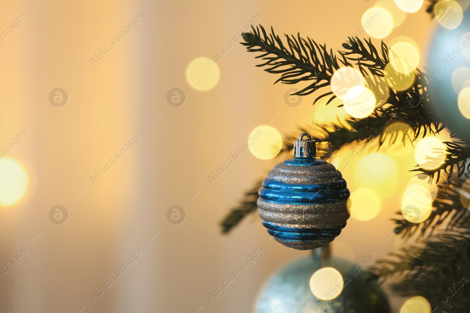 Photo of Christmas tree decorated with light blue festive balls on blurred background, closeup. Space for text