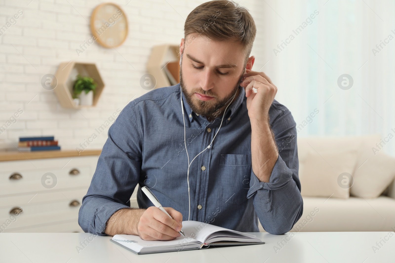 Photo of Young man with earphones holding online webinar indoors, view from webcam