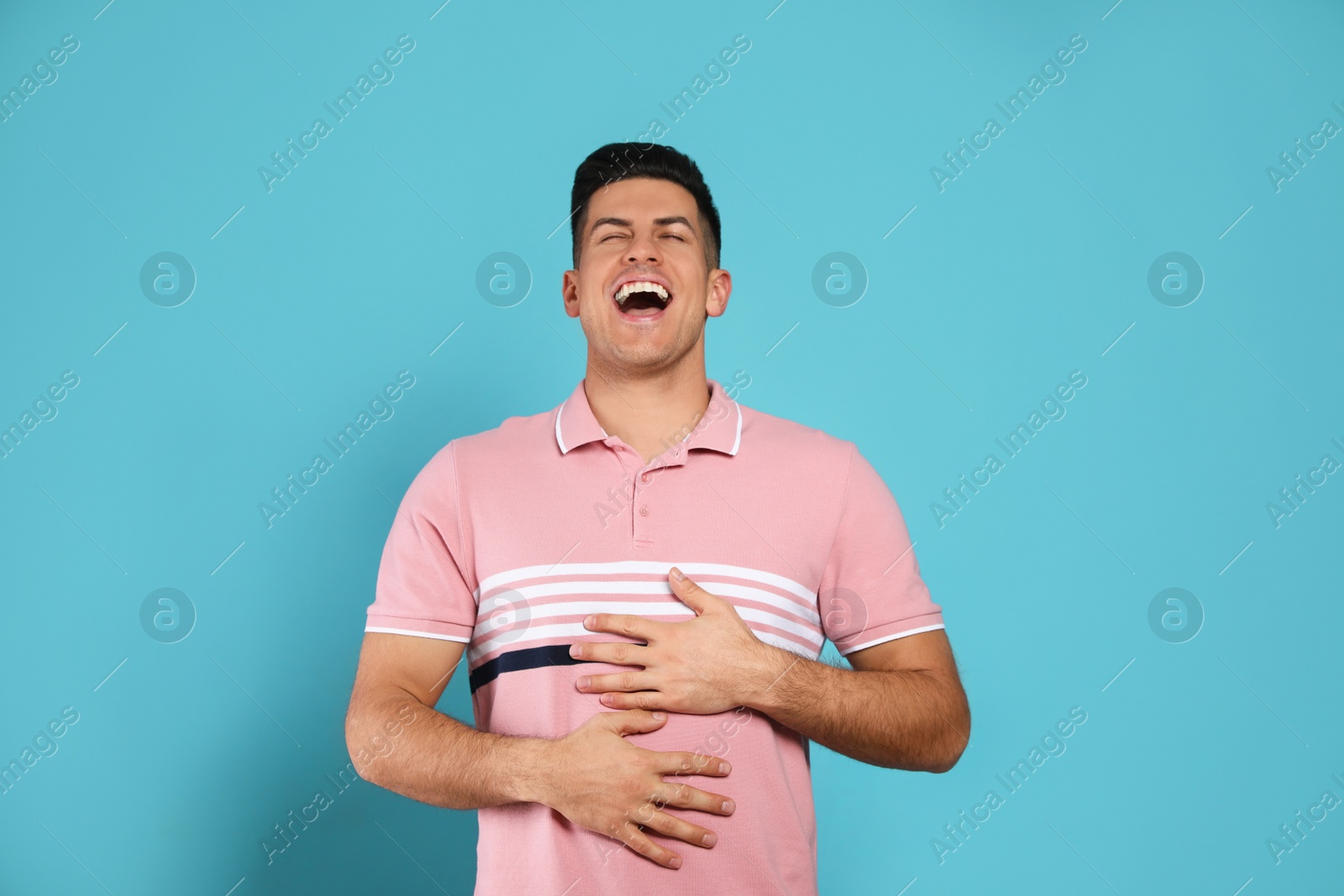 Photo of Handsome man laughing on light blue background. Funny joke