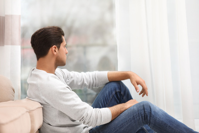 Photo of Handsome man resting near window at home