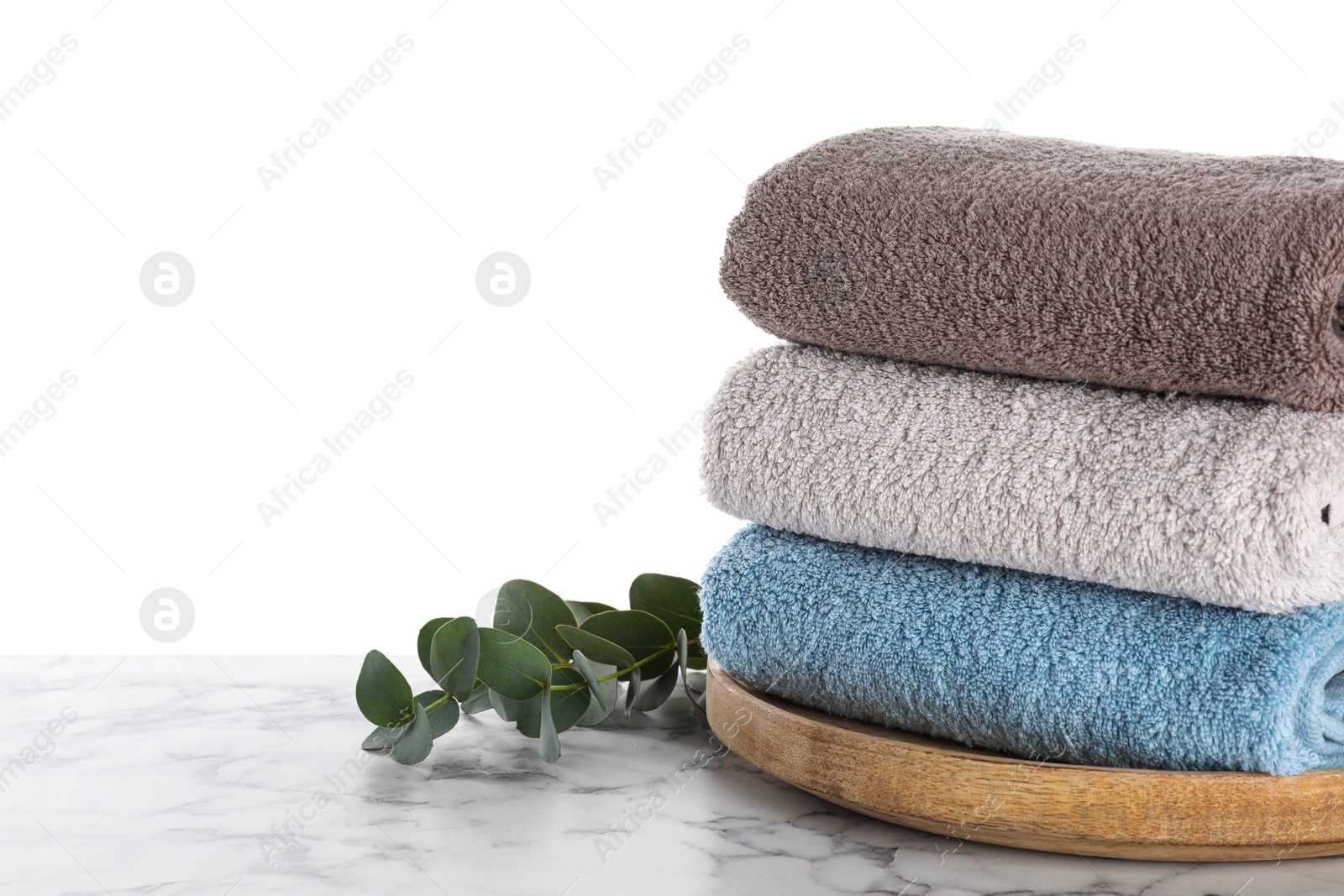 Photo of Fresh towels and eucalyptus branches on marble table against white background. Space for text