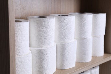Photo of Stacked toilet paper rolls on wooden shelf